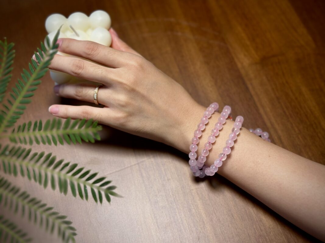 Rose Quartz necklace placed over heart chakra during meditation, with candles and earthy elements.