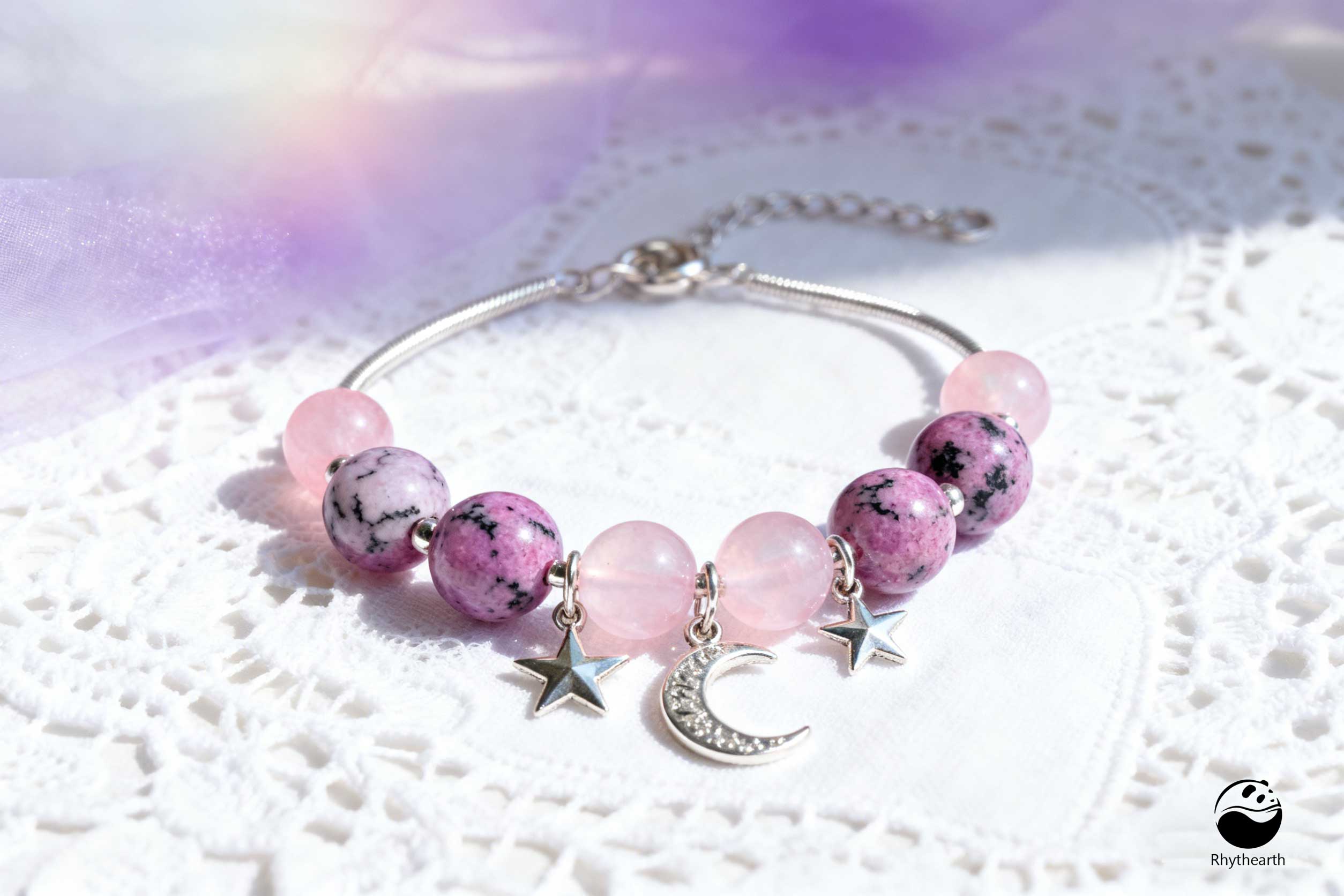 Hold and Reflect: She holds the rhodonite in one hand and the pink opal in the other.